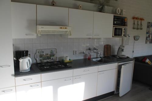 辛佩尔费尔德Rustige, gelijkvloerse vakantiewoning met 2 slaapkamers in Simpelveld, Zuid-Limburg的厨房配有白色橱柜和炉灶烤箱。