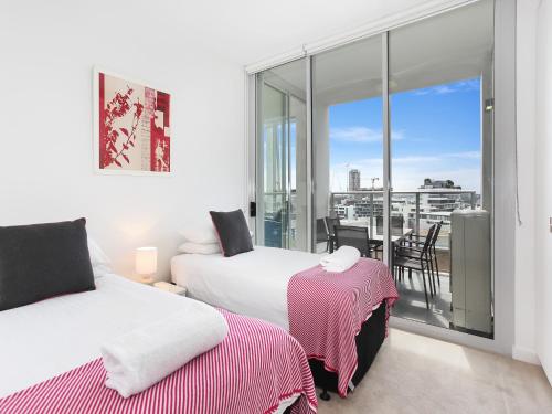 悉尼As the Sun Sets - Modern and Spacious 2BR Zetland Apartment Facing the Setting Sun的一间卧室设有两张床和一个美景阳台