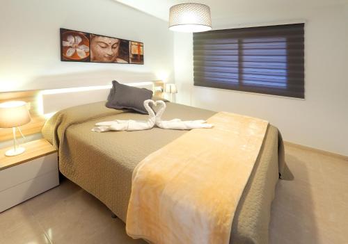 厄尔梅达诺La Perla: Sea View and Pool (family apartment)的一间卧室配有一张带天鹅的床