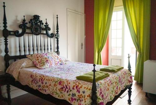 蓬塔德尔加达Azores Dream Hostel的一间卧室配有一张带木制床头板和绿色窗帘的床。
