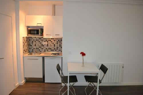 马德里大街公寓酒店的小厨房配有白色的桌子和椅子