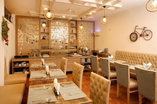 古尔冈Ahuja Residency Parklane, Gurgaon的一间带桌椅和柜台的餐厅