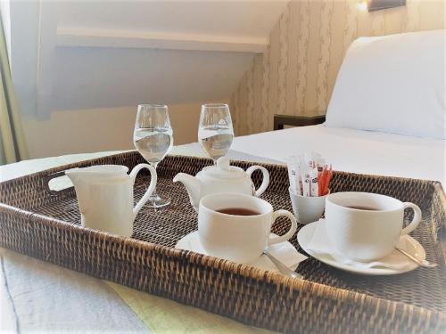 巴黎亨利四世左岸酒店的床上的盘子,上面装有杯子和酒杯