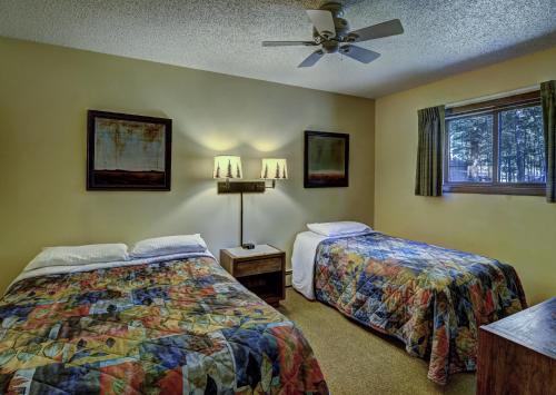 伊格尔里弗Lake Forest Resort的一间卧室配有两张床和吊扇