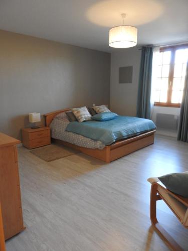 VillarsLes Petits Cléments的一间卧室配有一张带蓝色床单的床和床头柜。