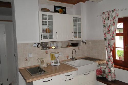 多纳瓦利多姆塞克惊奇钟声旅馆的厨房配有白色橱柜、水槽和窗户。