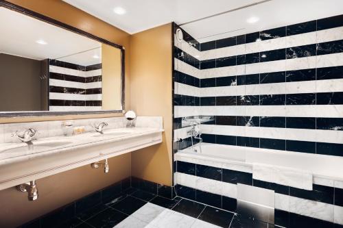 斯德哥尔摩Stallmästaregården Hotel, Stockholm, a Member of Design Hotels的浴室设有2个水槽、浴缸和镜子