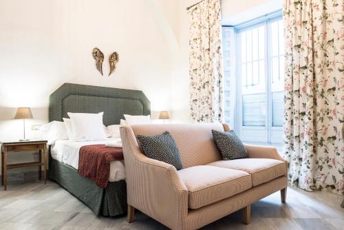 塞维利亚帕拉克玛尔姆乐斯公寓式酒店的一间卧室配有一张床、一张沙发和一把椅子