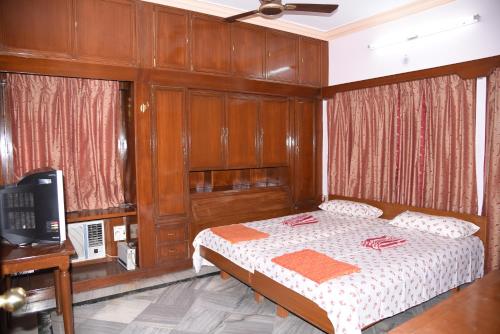 海得拉巴anjani mansion的一间卧室配有一张木镶板床和一台电视。