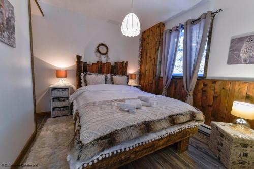 拉马巴耶Le Vanilee - Les Chalets Spa Canada的一间带一张大床的卧室,位于带木墙的房间