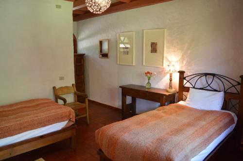 Hurtado洛斯安第斯庄园酒店的一间卧室配有两张床、一张桌子和一把椅子