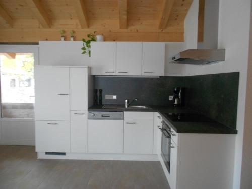 莱奥冈Appartement Haus Petra的厨房配有白色橱柜和黑色台面