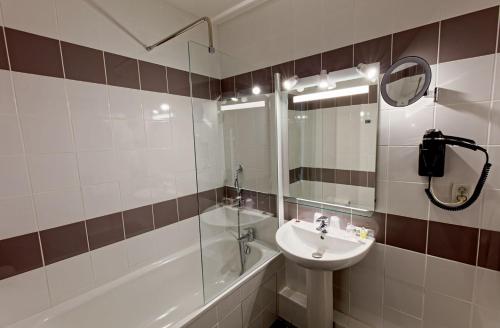 热纳KYRIAD LYON EST - Genas Eurexpo的浴室配有盥洗盆、镜子和浴缸