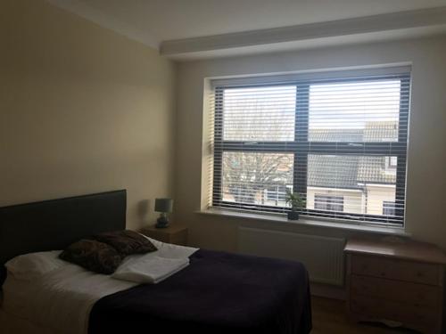 斯劳slough central - spacious 2 bedroom, 2 bathroom apartment的一间卧室设有一张床和一个大窗户