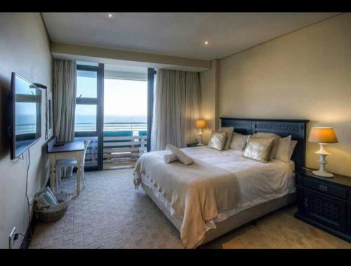 德班The Pearls of Umhlanga - Ocean view Apartments的一间卧室配有一张床、一张书桌和一台电视