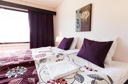 约恩苏Hotel Julie的一间卧室配有一张带紫色枕头的床