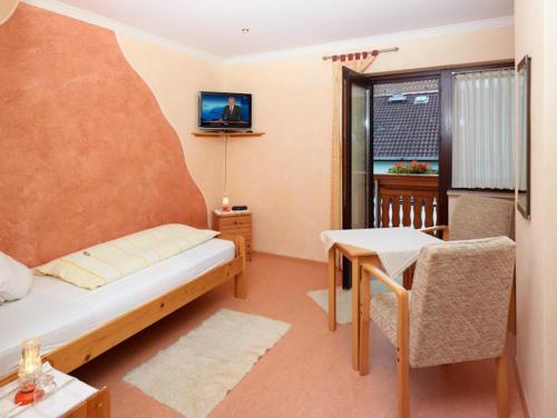 BirgelHotel Garni Assion的配有床、桌子和电视的房间