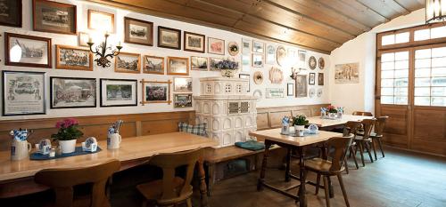 加尔米施-帕滕基兴威尔登菲尔赛霍夫酒店的餐厅设有桌椅,墙上挂有图片