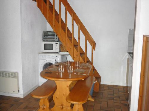 卡布勒通Holiday Home Paradise Océan-5 by Interhome的楼梯旁的一张带椅子的木桌