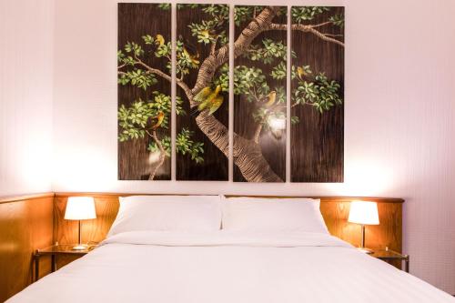 日内瓦Hotel Sagitta的卧室配有一张床,墙上挂有绘画作品