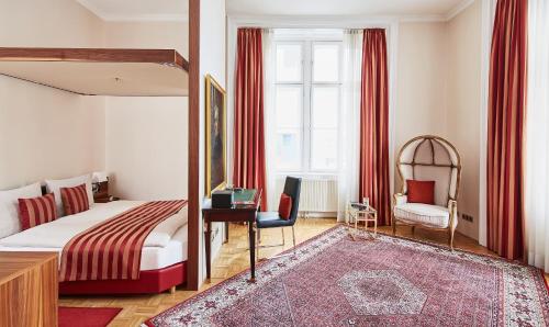 维也纳Living Hotel an der Oper的一间卧室配有一张床、一张桌子和一把椅子