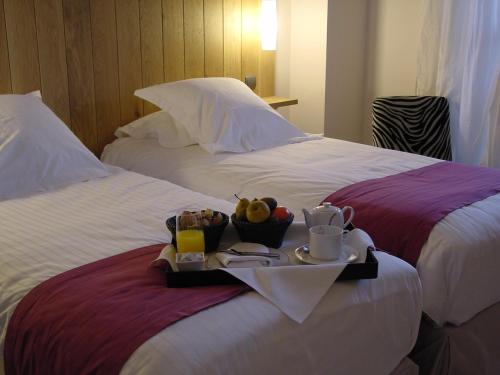 穆瓦萨克船主酒店的一张盛放食物和饮料的托盘,放在两张床上