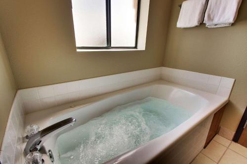沙德伦Best Western West Hills Inn的浴室设有装满水的浴缸。