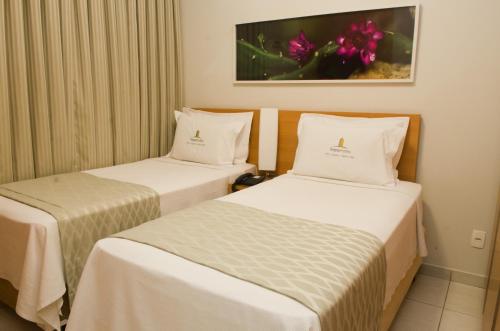 贝洛奥里藏特西达德新星伊姆帕尔套房酒店的配有白色床单的酒店客房内的两张床