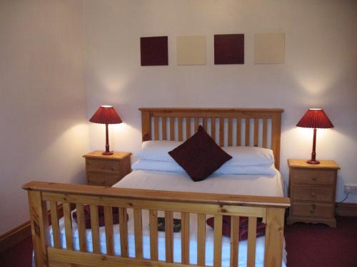 奇彭纳姆The Jolly Huntsman的一间卧室配有一张木床、两个床头柜和两盏灯。