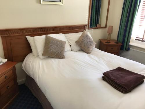北安普敦格拉夫顿客房酒店的一张白色的床,上面有一个棕色的袋子