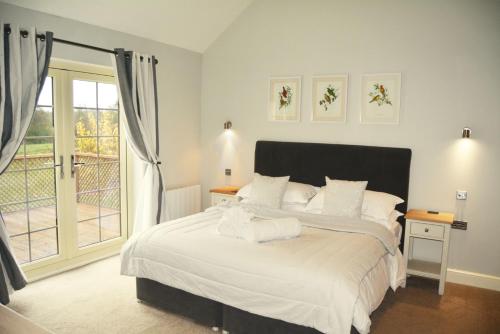 ChappelWoodbell Lodge的一间卧室配有一张带白色床单的床和一扇窗户。