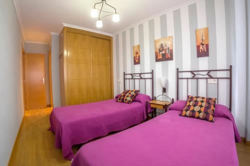 里瓦德塞利亚Apartamento Sella y Mar - VUT12AS的紫色床单的客房内的两张床