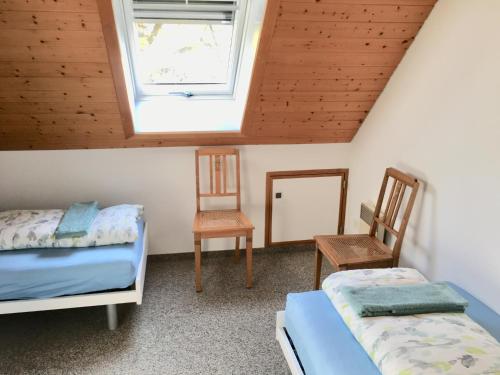 BischofszellSitter-Panorama的一间卧室设有两张床、一个窗口和两把椅子