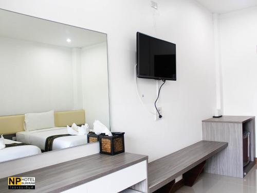 武里南NP酒店的酒店客房设有一张床和墙上的电视