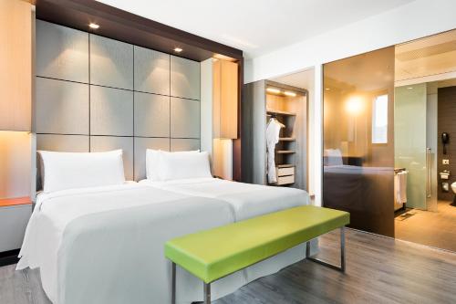 巴塞罗那Hotel Barcelona Condal Mar Affiliated by Meliá的卧室配有一张白色大床和绿色长凳