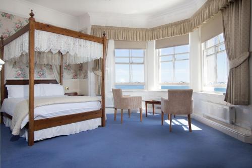 彭赞斯奎恩斯酒店的一间卧室配有天蓬床和桌椅