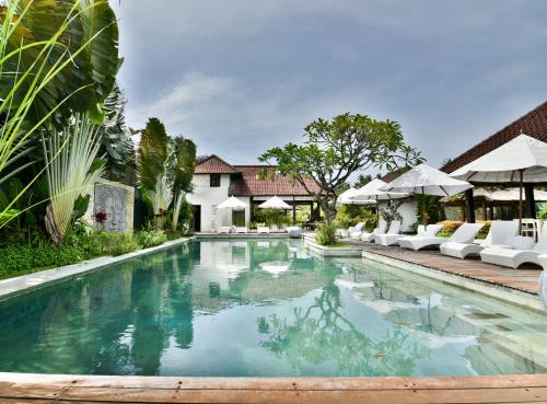 沙努尔Katala Suites and Villas的别墅内的游泳池配有白色椅子