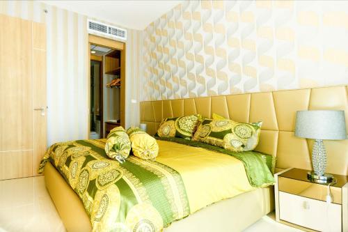 北芭堤雅SL奢华风格生活3号公寓的一间卧室配有一张带黄色和绿色枕头的床