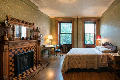 纽约哈林福罗普小屋酒店的一间卧室配有一张床、一个壁炉和一张书桌