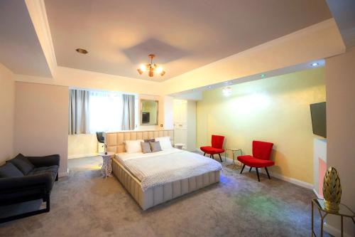 布加勒斯特Brater Luxury的一间卧室配有一张床和两张红色椅子