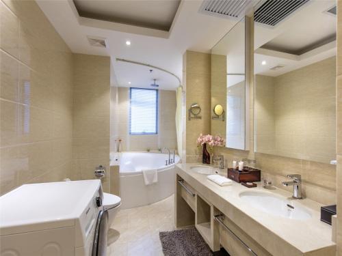 天津天津中北艾丽华酒店及服务公寓的浴室配有2个盥洗盆、浴缸和浴缸。