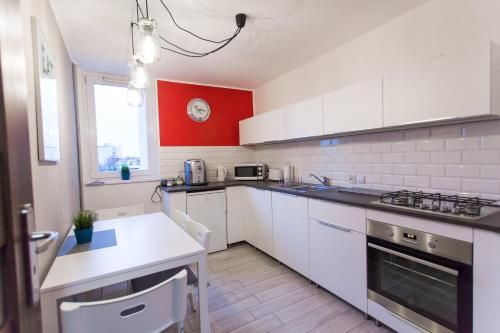 托伦Nest Arena Toruń的厨房配有白色橱柜和红色墙壁