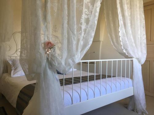 Squinzano马塞里亚圣保罗酒店的一张带白色窗帘和花的婴儿床