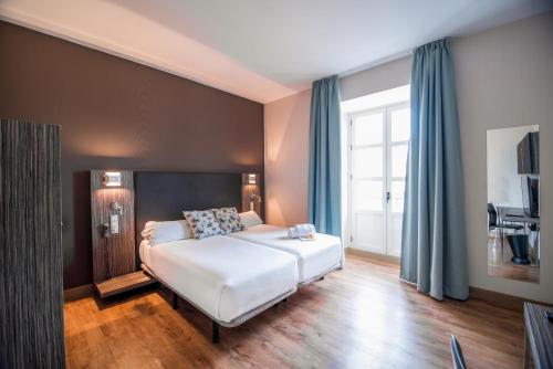塞维利亚珀蒂帕拉斯圣克鲁斯酒店的卧室配有一张带蓝色窗帘的大型白色床