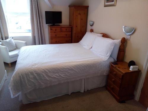 凯西克Dunsford Guest House的卧室配有白色床、梳妆台和椅子