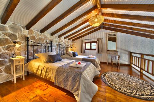 朗戈斯Glyfada Beach Villas的一间卧室设有两张床和石墙