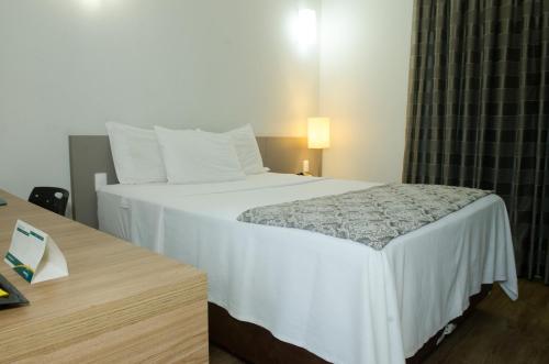 贝洛奥里藏特营帕埃克斯颇敏纳斯公寓的卧室配有一张白色的大床和一张桌子