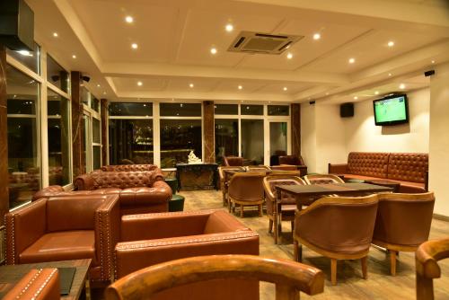 达兰萨拉Asia Health Resorts & Spa的餐厅设有皮椅、桌子和电视