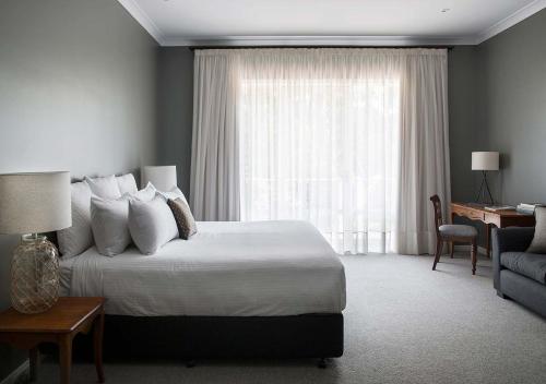 雷德山Lancemore Lindenderry Red Hill的一间卧室配有一张床、一张书桌和一个窗户。