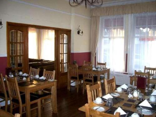 伯恩茅斯金斯利酒店的用餐室设有木桌、椅子和窗户。